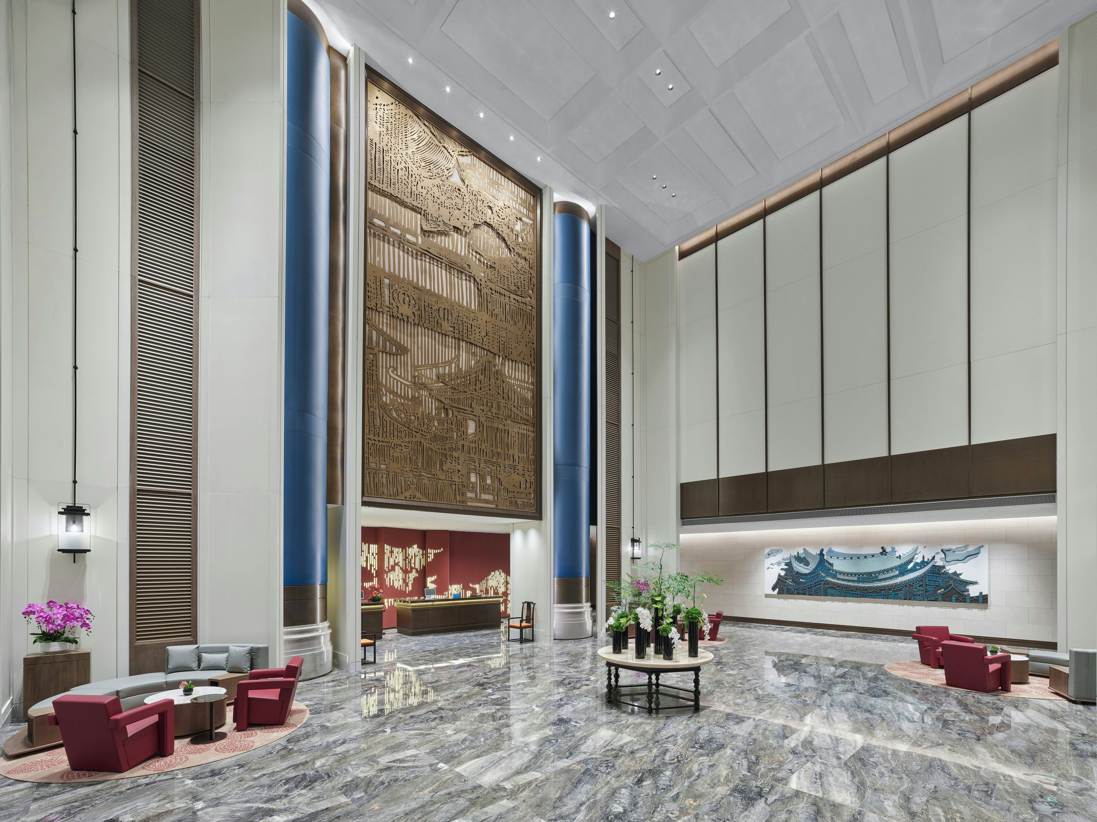 A spacious lobby with a reception desk, seating area, and a large decorative wall.