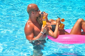 Um casal em uma piscina com um brinquedo inflável rosa.