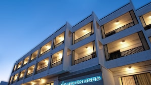 Un hotel de varios pisos con ventanas iluminadas y balcones, que presenta un letrero de neón llamativo en la planta baja.