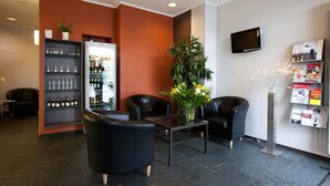 Ein Empfangsbereich mit Bar, Sitzgelegenheiten, einem Fernseher und einer Zeitschriftenauslage.