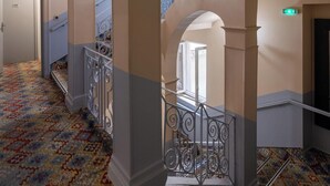 A grand hallway with high ceilings, ornate columns, and a patterned carpet. - Hôtel Danieli Avignon (Avignon)