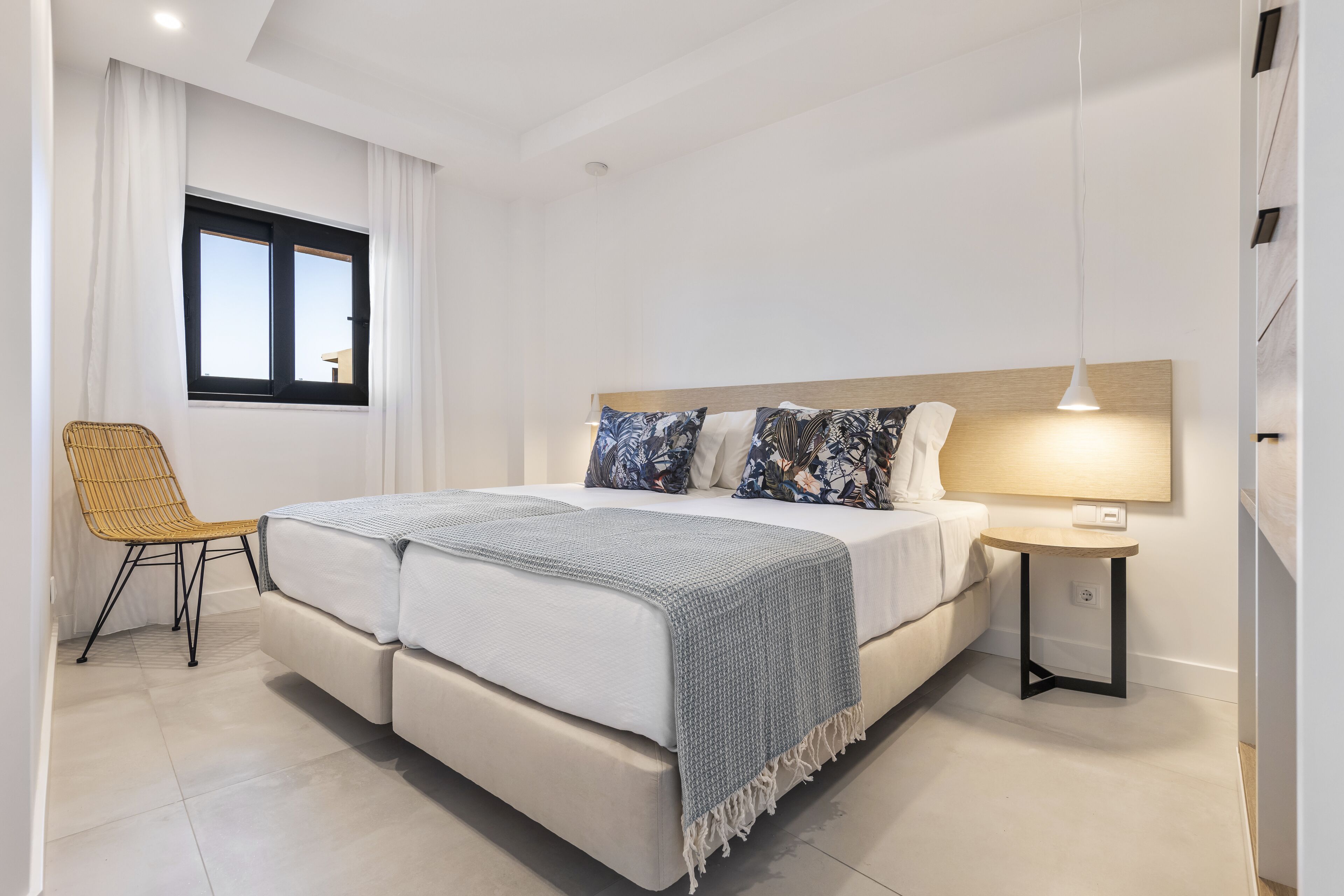 Une chambre moderne avec un lit double, une table de chevet, une chaise et une fenêtre avec des rideaux.