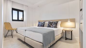 Une chambre moderne avec un lit double, une table de chevet, une chaise et une fenêtre avec des rideaux.