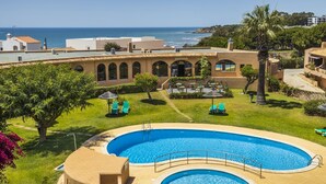 Un complex turístic amb piscina, zona d'estar a l'aire lliure i vista al mar.