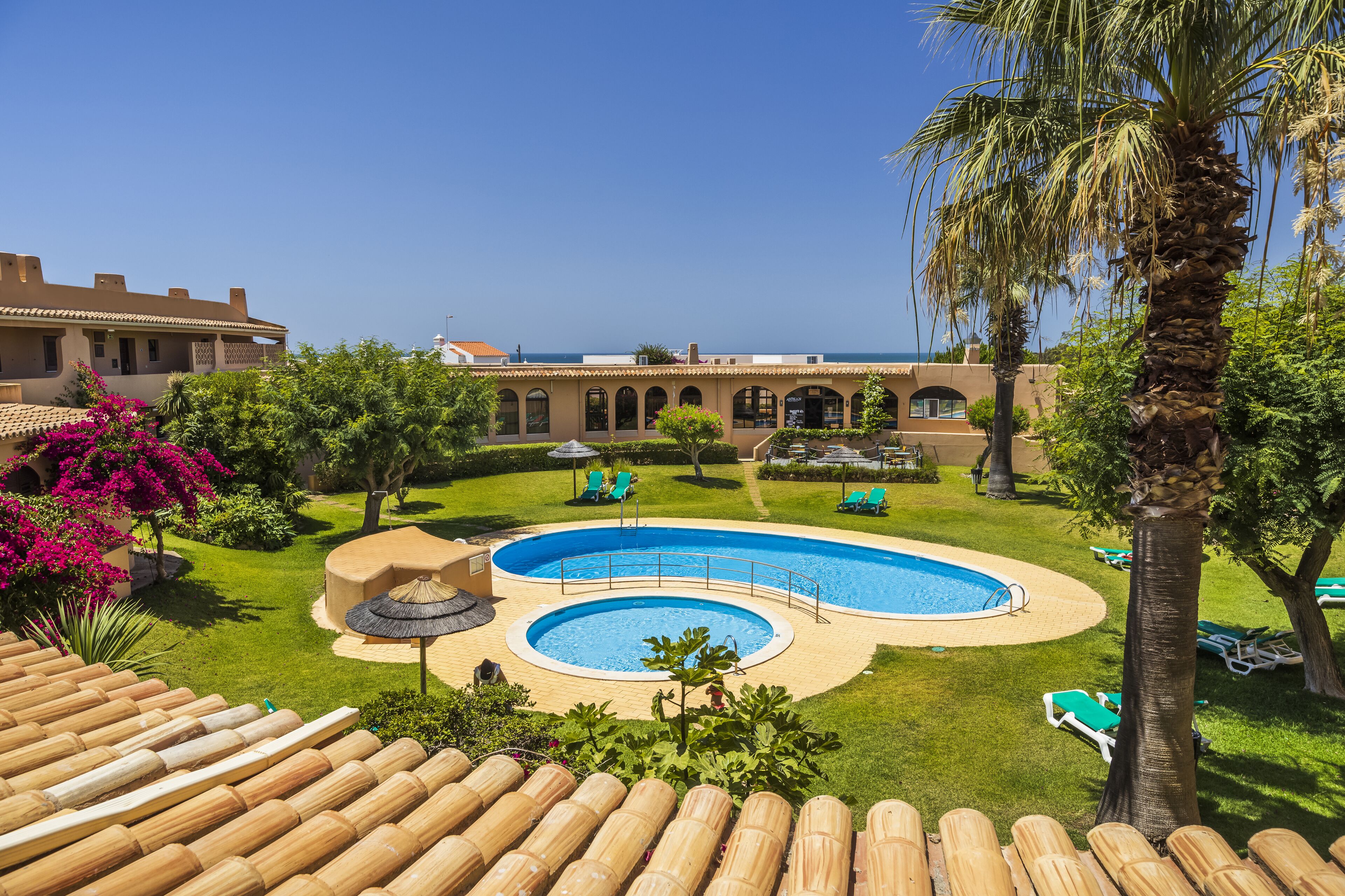 Un resort con una piscina grande, sillas de descanso y vistas al océano.