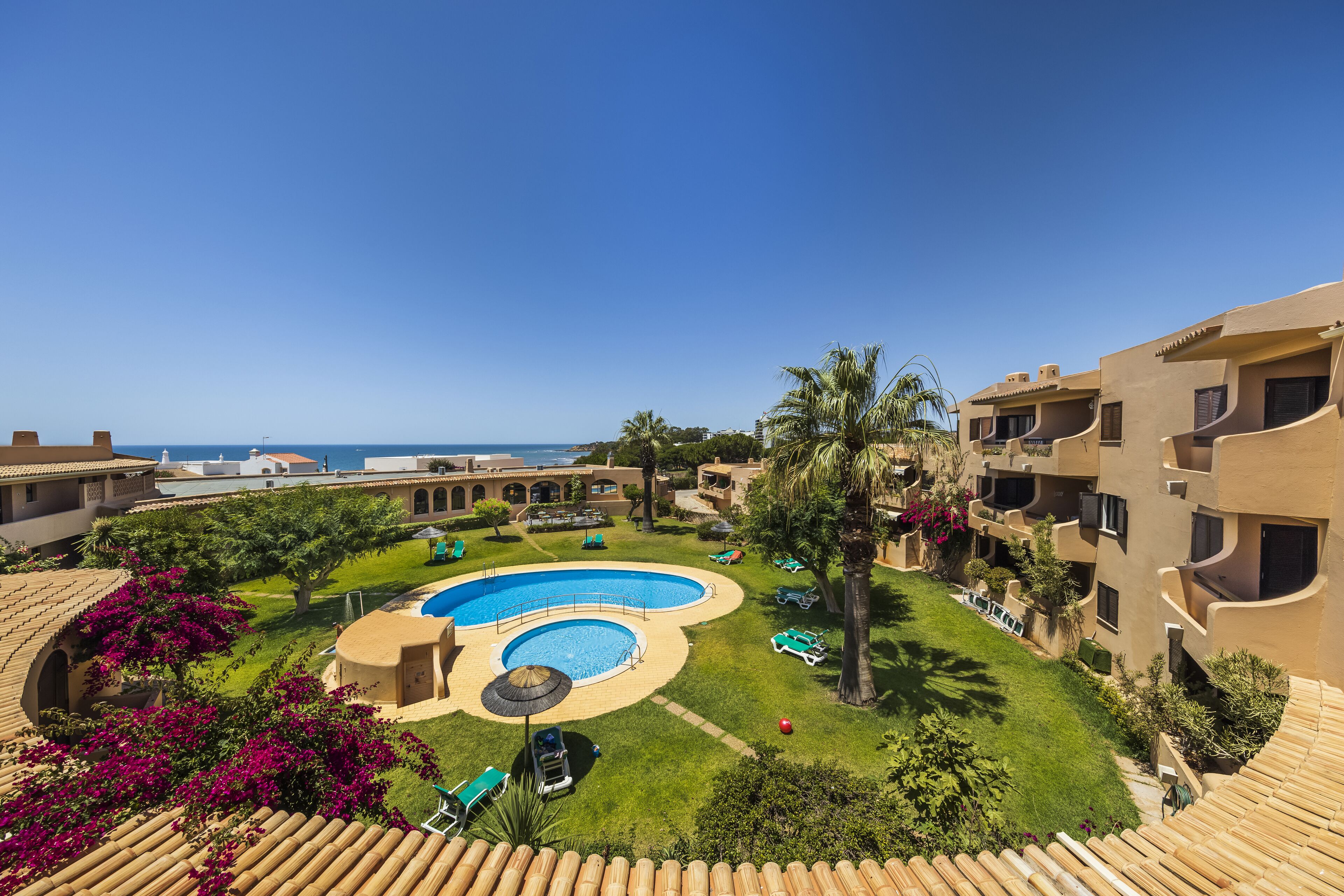 Ein Resort mit großem Pool, Palmen und Blick auf den Ozean.