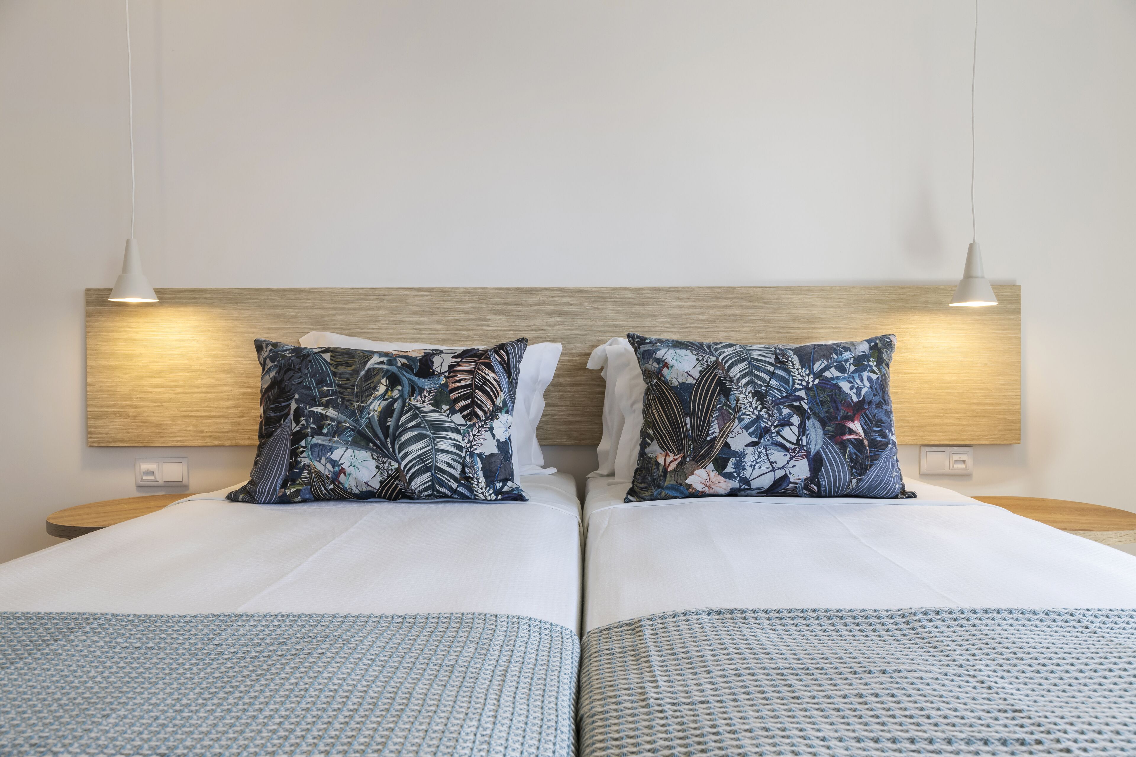 A double bed with a wooden headboard, two matching pillows, and a patterned bedspread.