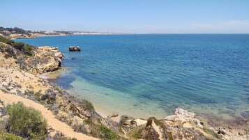 En la playa, arena blanca, sillas reclinables de playa, sombrillas