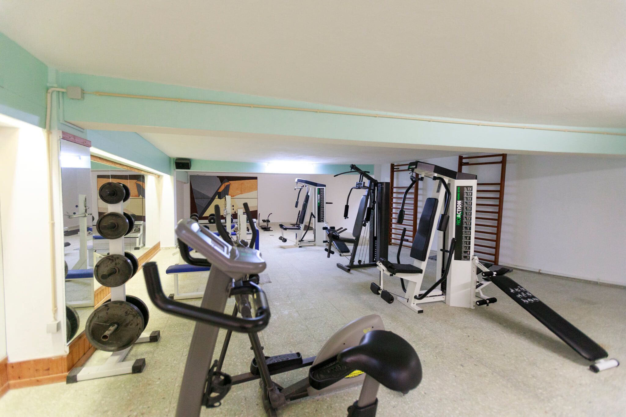 A gym with various exercise equipment including treadmills, weight machines, and free weights.