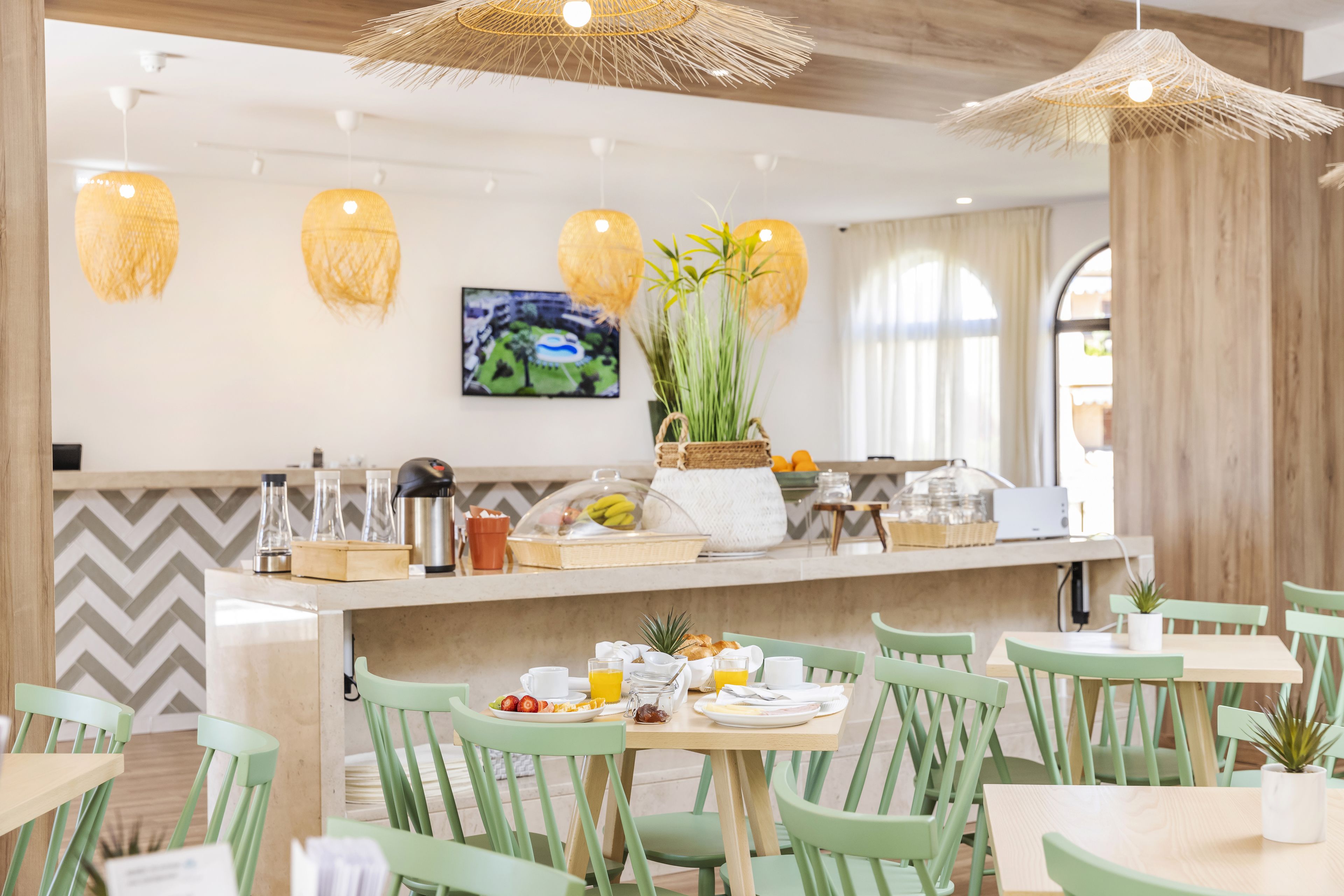 A breakfast setup with a counter, chairs, and a table with breakfast items.