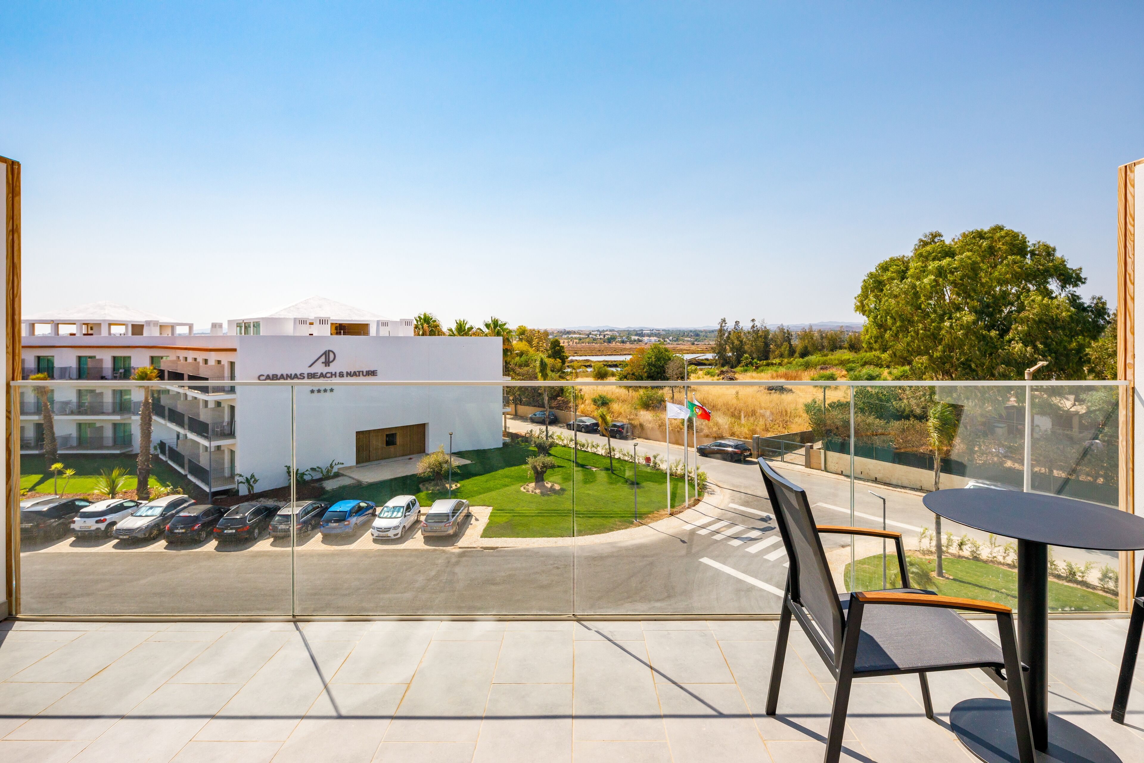 Un balcón con vista a un estacionamiento y un edificio que dice "CABANAS BEACH & NATURE".