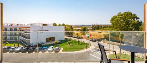 Un balcón con vista a un estacionamiento y un edificio que dice "CABANAS BEACH & NATURE".