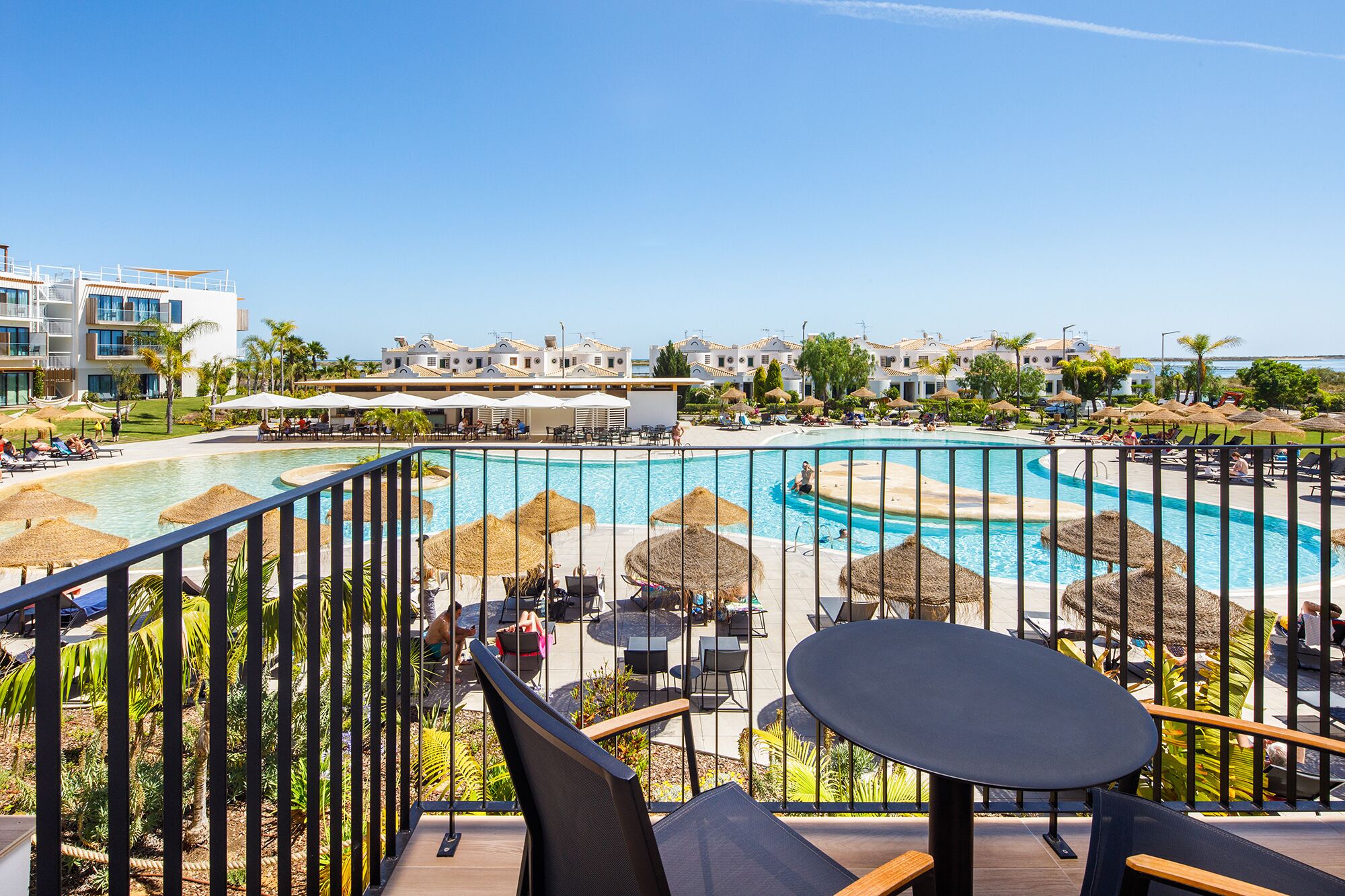 A resort pool area with multiple swimming pools, lounge chairs, and umbrellas.