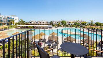 A resort pool area with multiple swimming pools, lounge chairs, and umbrellas.