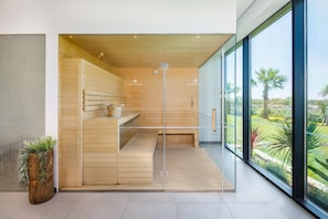 Habitación de hotel moderna con interior de madera, ventanas amplias y vistas a un jardín ajardinado.