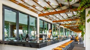 A modern bar area with a long counter, bar stools, and a wooden ceiling. - AP Cabanas Beach & Nature - Adults Friendly (Tavira)