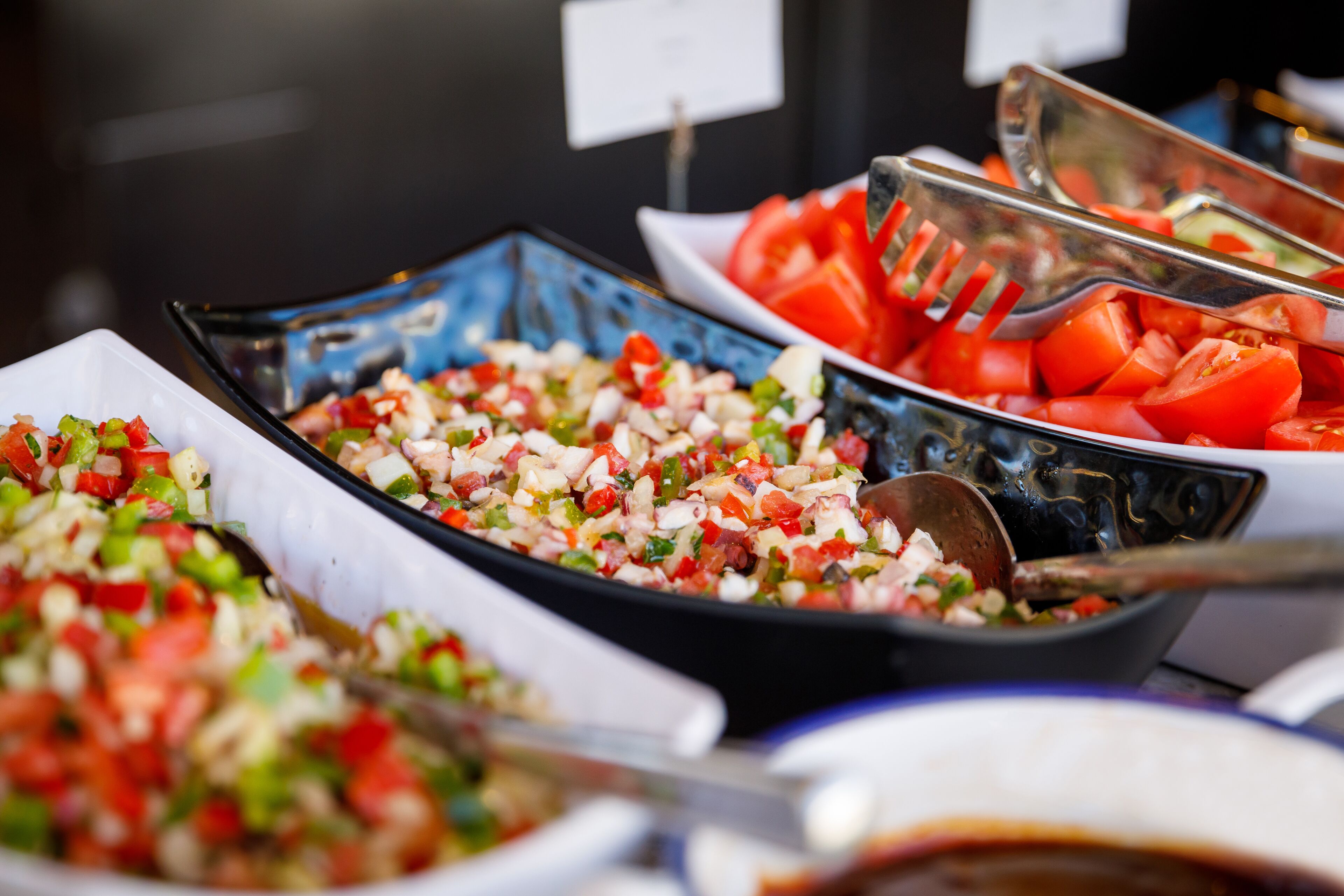 A buffet with various dishes including chopped vegetables and sliced tomatoes.