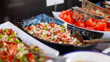 A buffet with various dishes including chopped vegetables and sliced tomatoes.