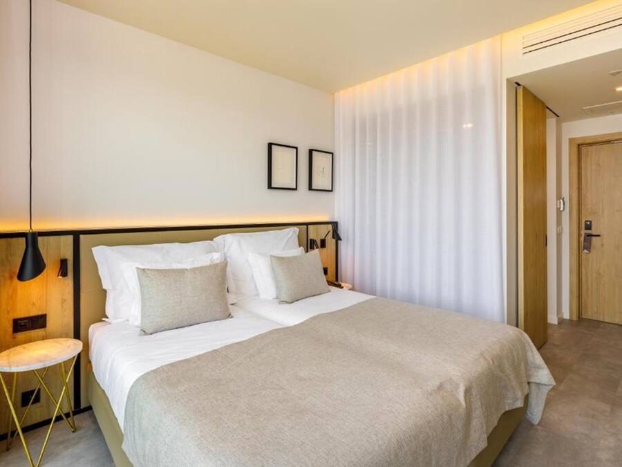 A modern hotel room with a large bed, a bedside table, and a nightstand.