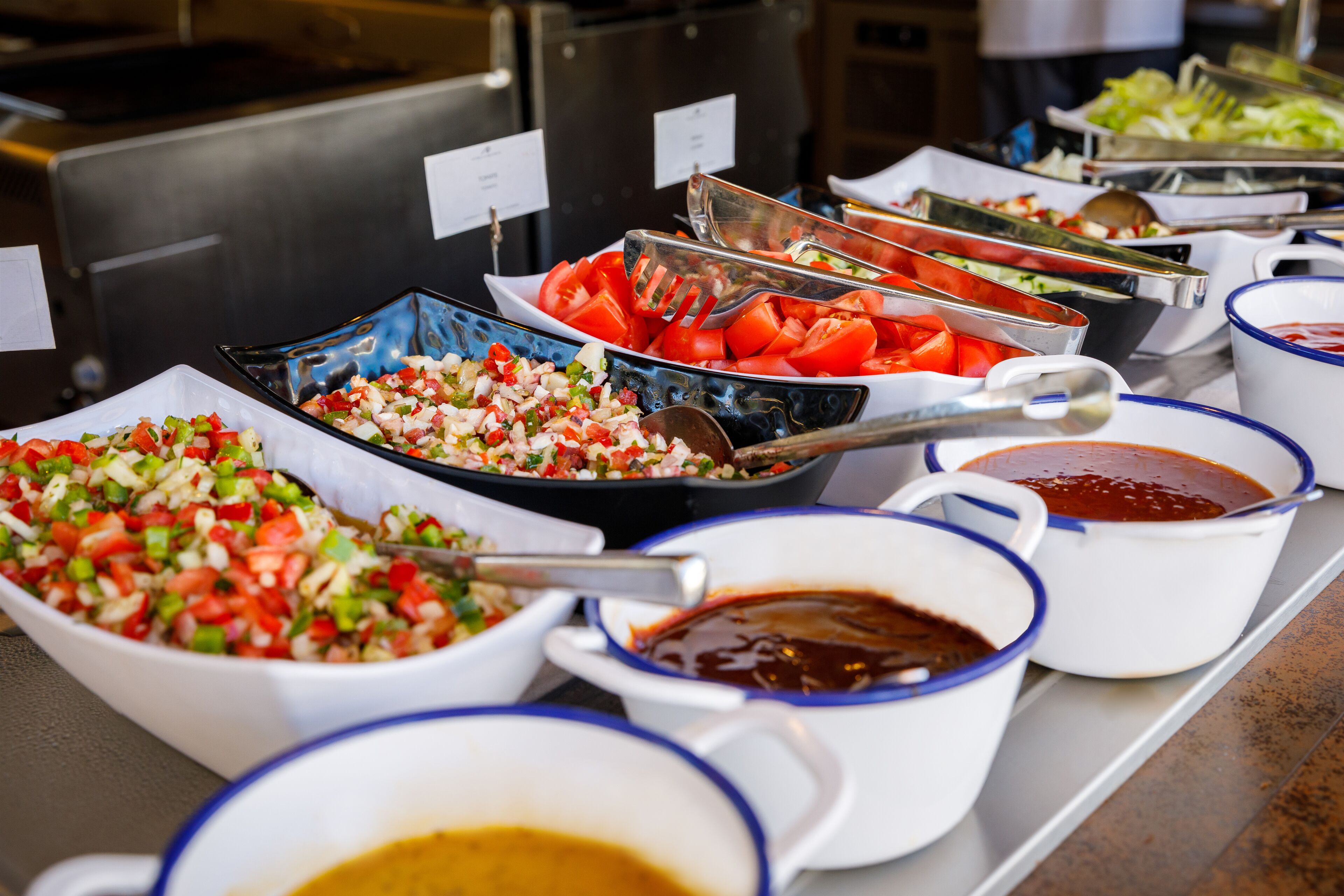 Ein Buffet mit verschiedenen Speisen, darunter Salate, Gemüse und Soßen.
