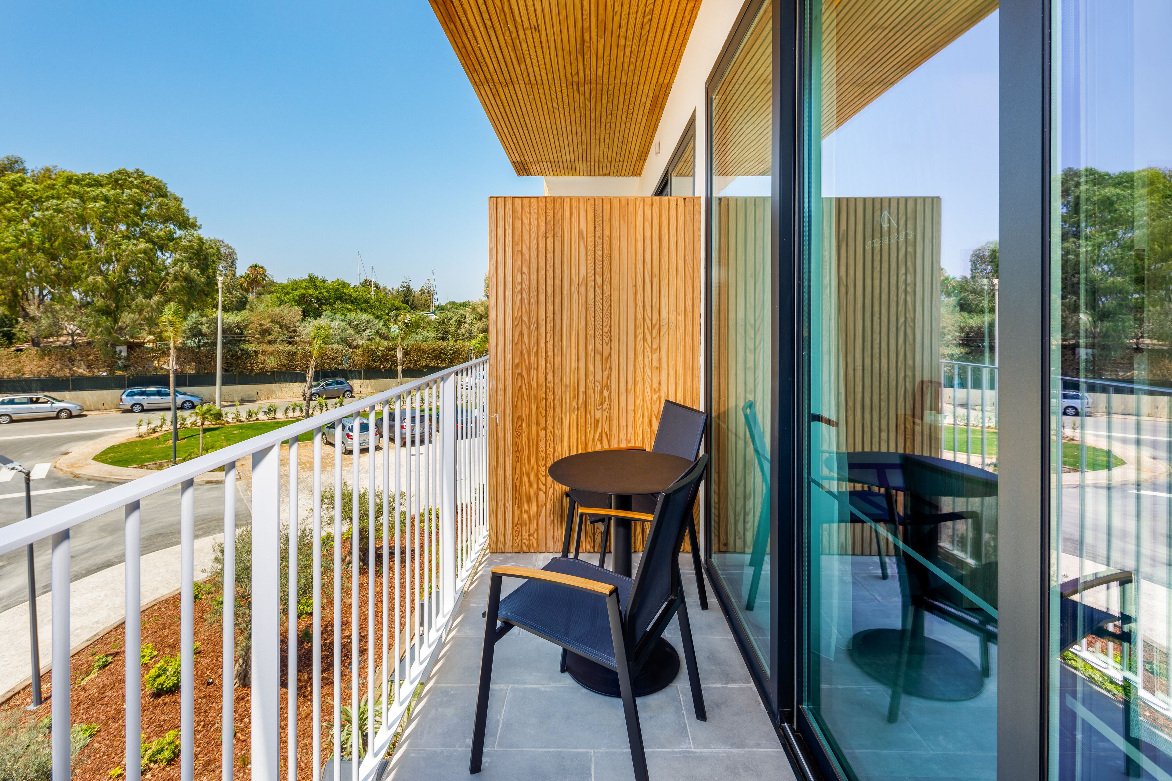 A balcony with a wooden ceiling, a glass wall, and a table with chairs.