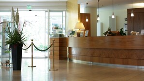 Et receptionområde med en træreception, en potteplante og en lampe.