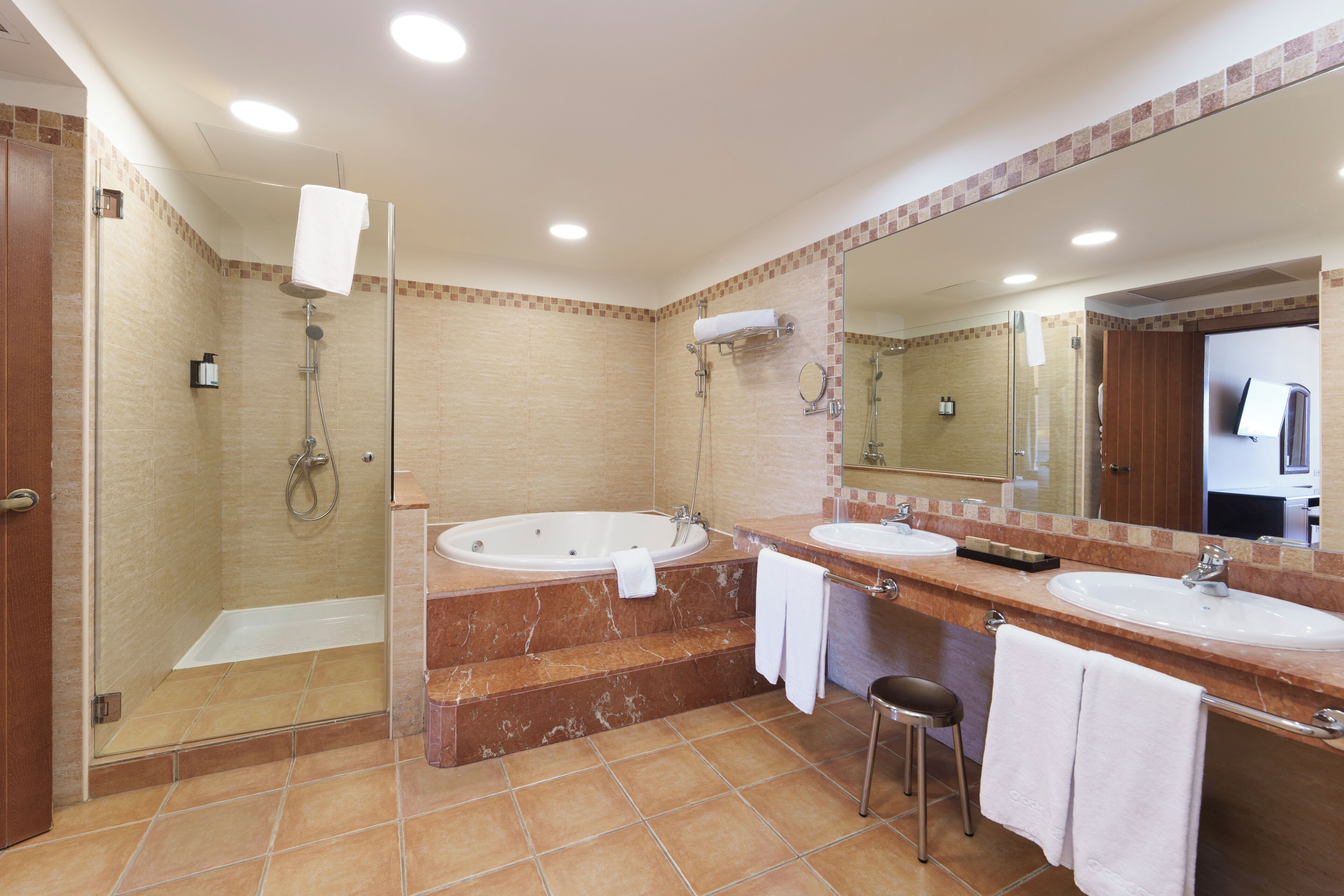 Un bagno moderno con doccia vetrata, una vasca da bagno ampia e due lavandini con uno specchio grande sopra.