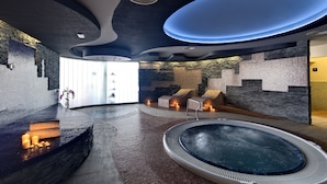 A modern spa area with a hot tub, seating, and a stone wall. - Occidental Jandía Playa (Pajara)