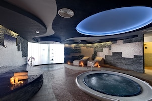 Een moderne spa met een bubbelbad, zitplaatsen en een stenen muur.