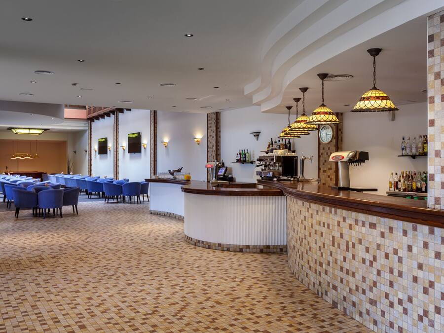 Vestíbulo de hotel con recepción, un reloj y zona de bar.
