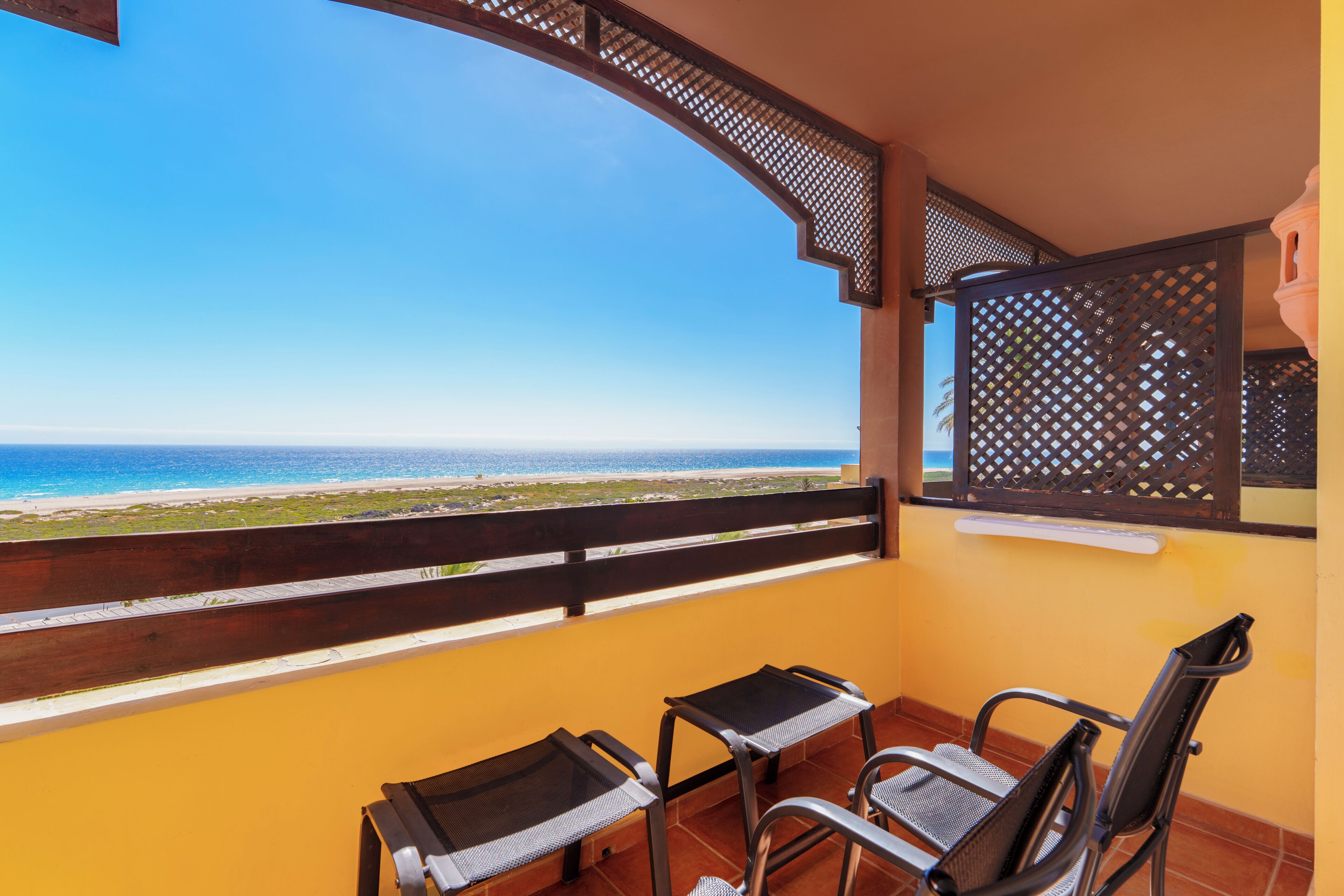 Un balcón con dos sillas y una mesa, con vista a la playa.