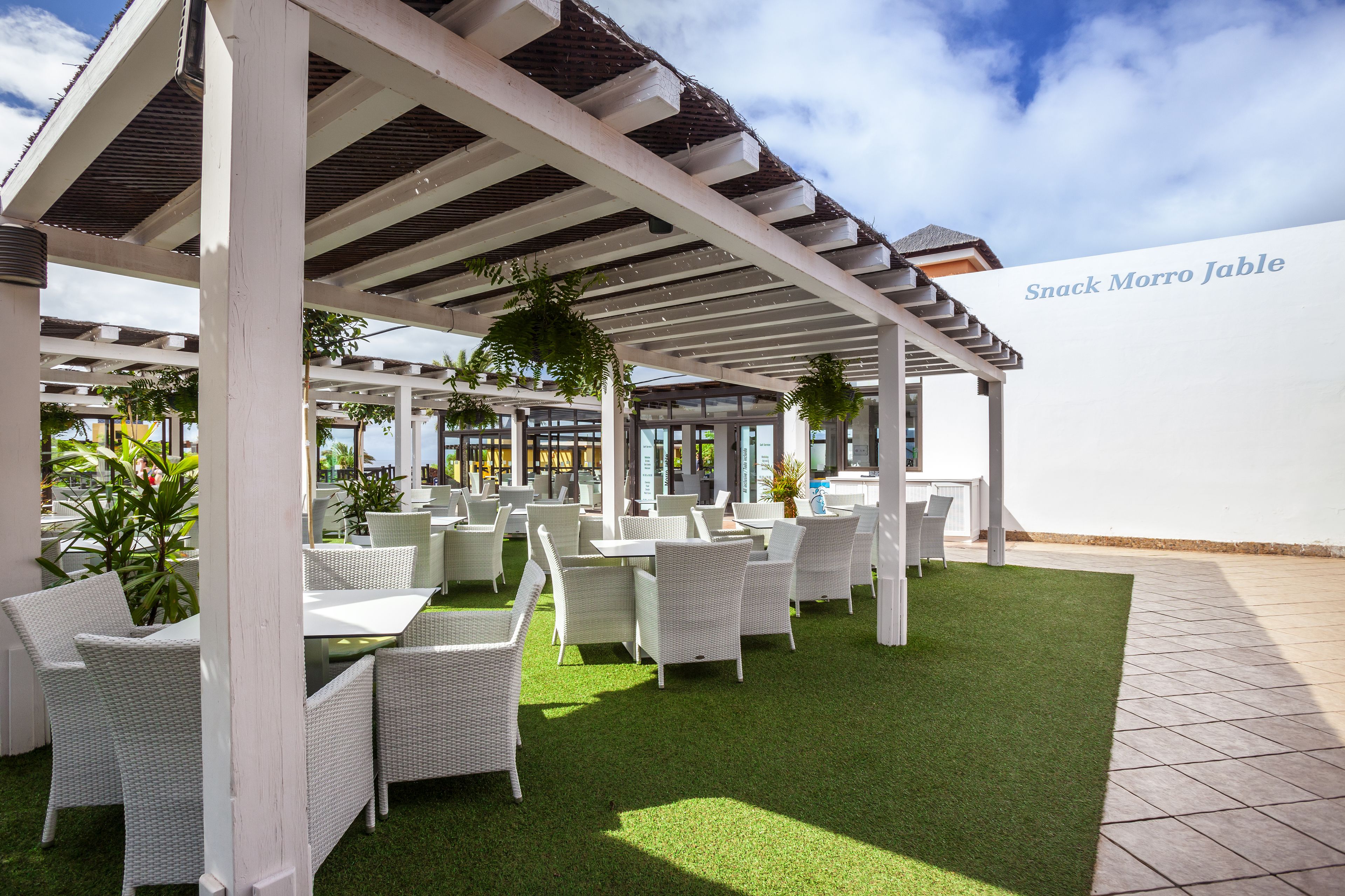 An outdoor seating area with white wicker furniture and a white pergola.