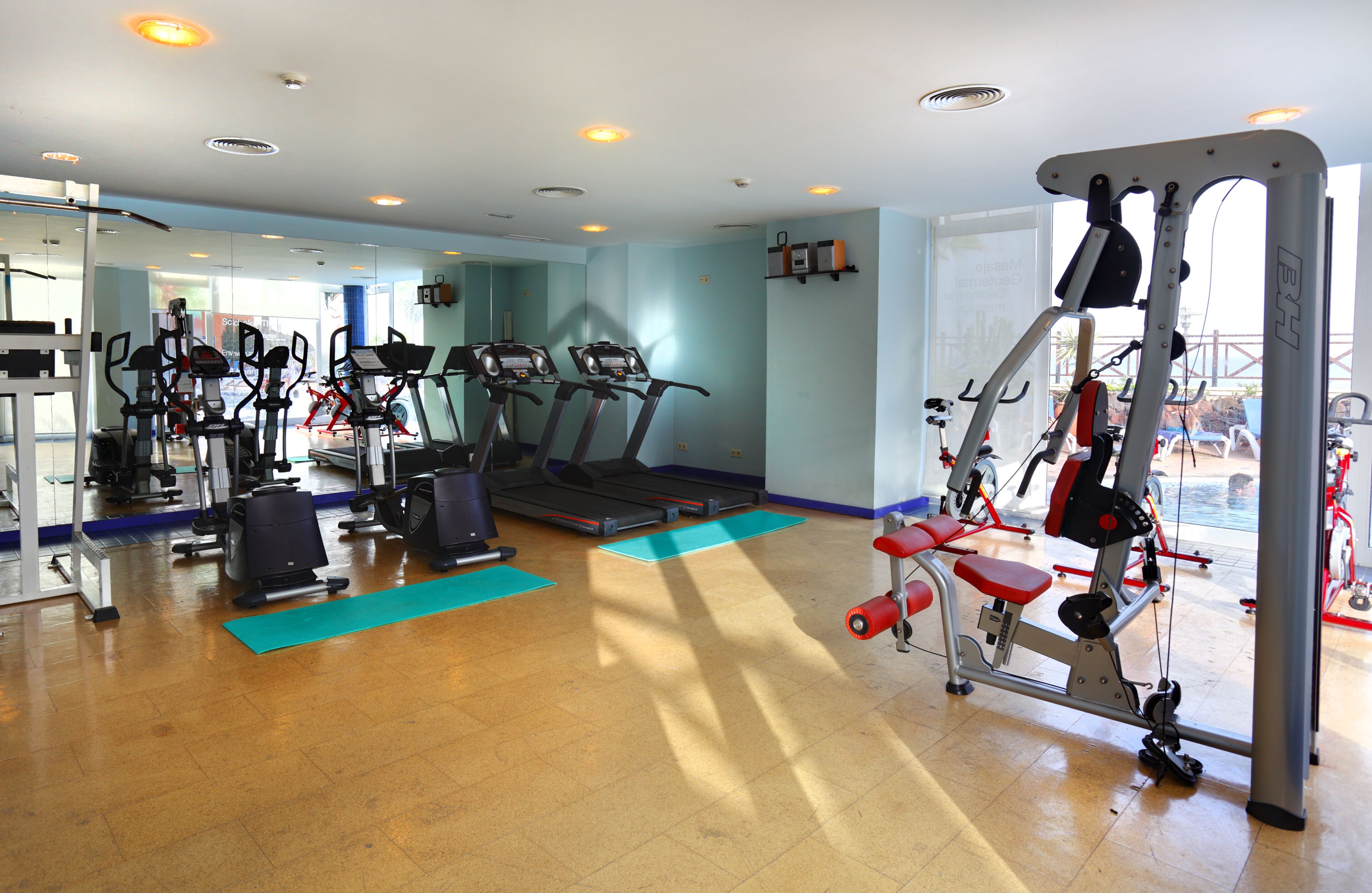 Un gimnasio con cintas de correr, elípticas y equipo de pesas.