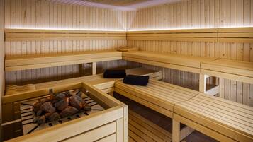 Una sauna con bancos de madera y un hogar central.