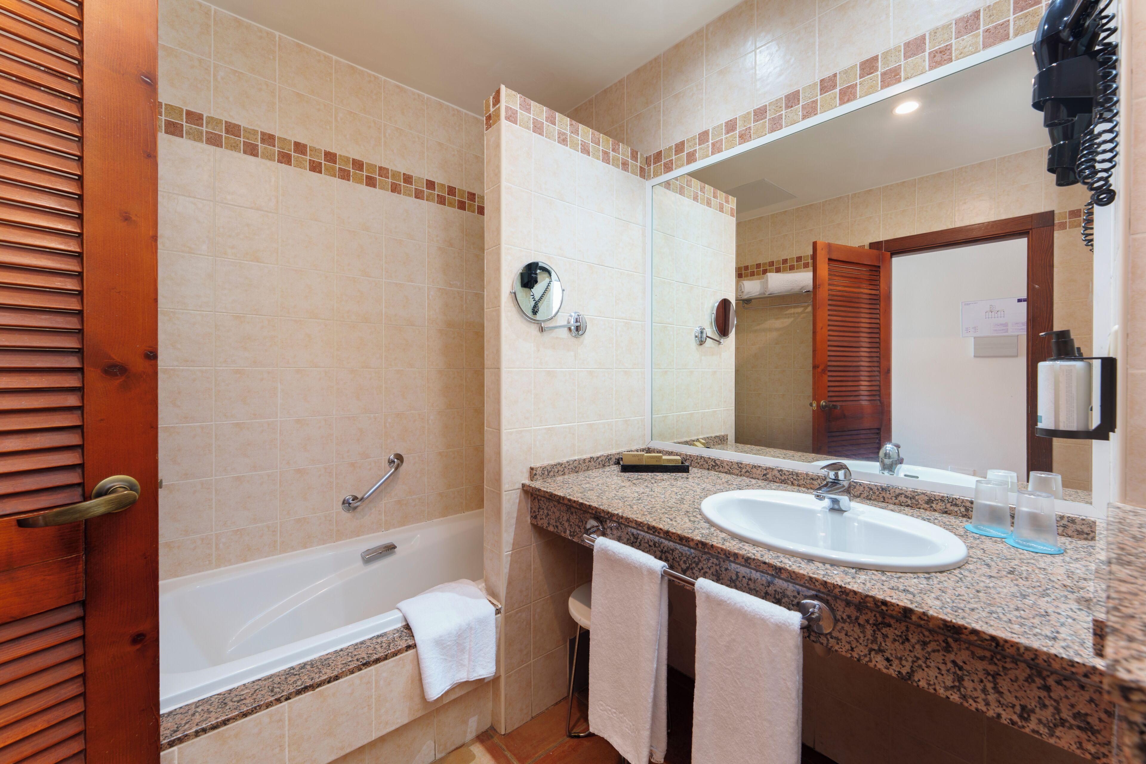 A bathroom with a bathtub, a sink, a mirror, and a towel rack.