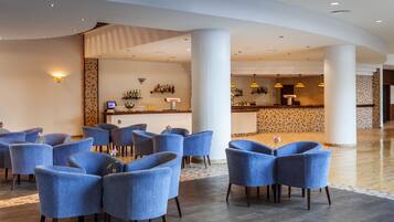 A hotel lobby with a bar area, seating with vases, and a patterned wall.