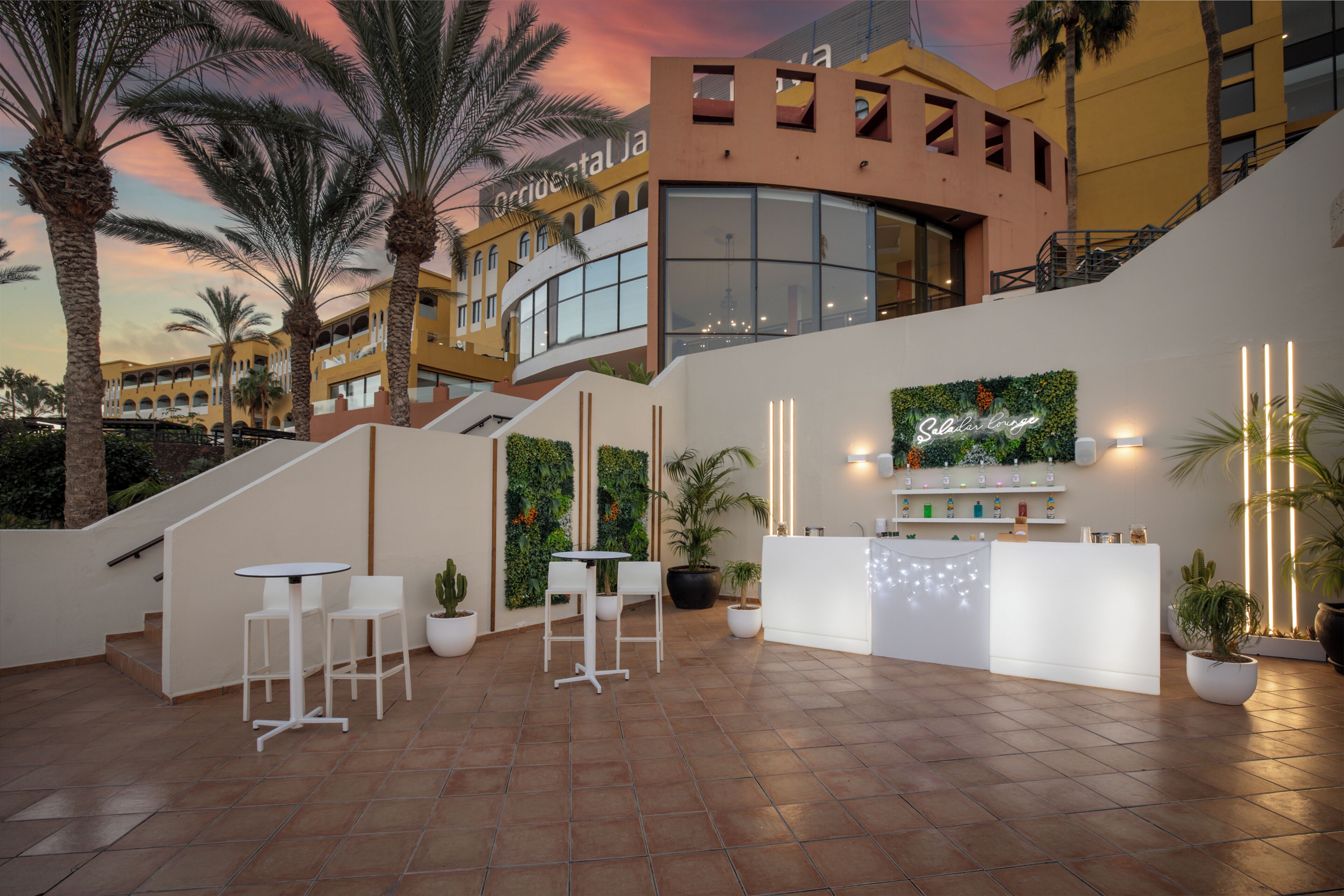 A modern hotel lobby with a reception desk, seating area, and a staircase leading to upper floors.