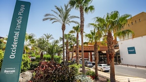 A sign for the Occidental Jandia Playa hotel, part of the Barceló Hotel Group, with palm trees and a clear sky. - Occidental Jandía Playa (Pajara)