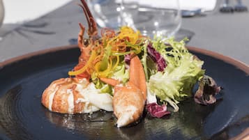 A dining table with a lobster dish, wine glasses, and a windmill in the background.