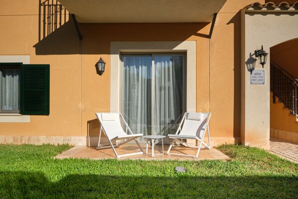 Un bâtiment doté d’un patio comprenant deux fauteuils blancs et une petite table.