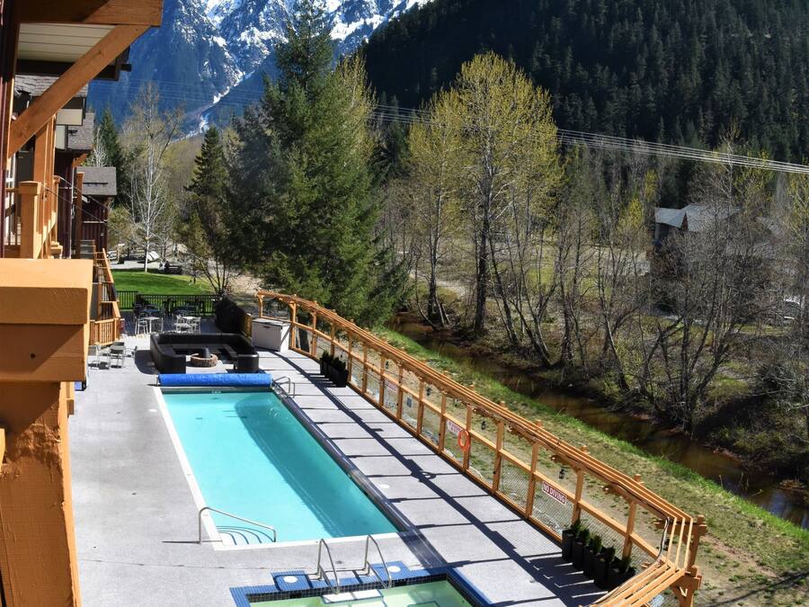 A pool area with a wooden deck and a view of snow-capped mountains.