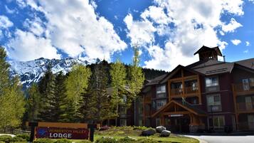 Een lodge met een bord waarop staat 'Pemberton Valley Lodge', omringd door bergen en bomen.