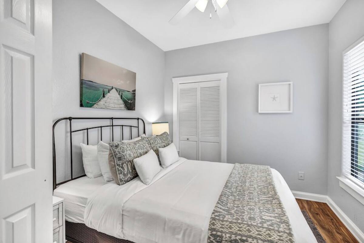 A bedroom with a bed, a nightstand, a ceiling fan, a window with blinds, and a door with a closet.