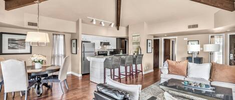 A spacious living area with a dining table, leather chairs, a sofa, and a glass coffee table.