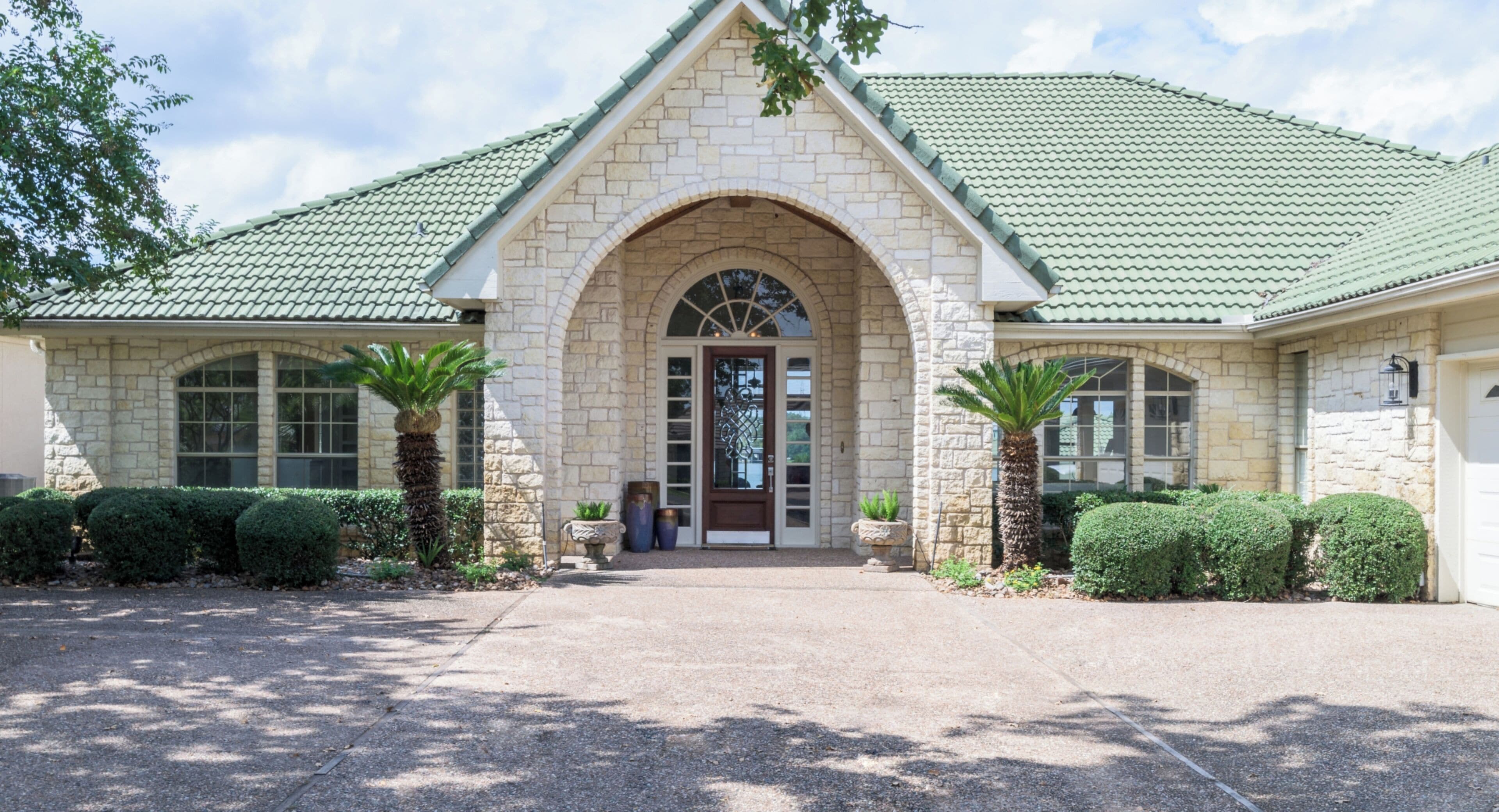 A stone building with a green roof, an arched entrance, and symmetrical windows.