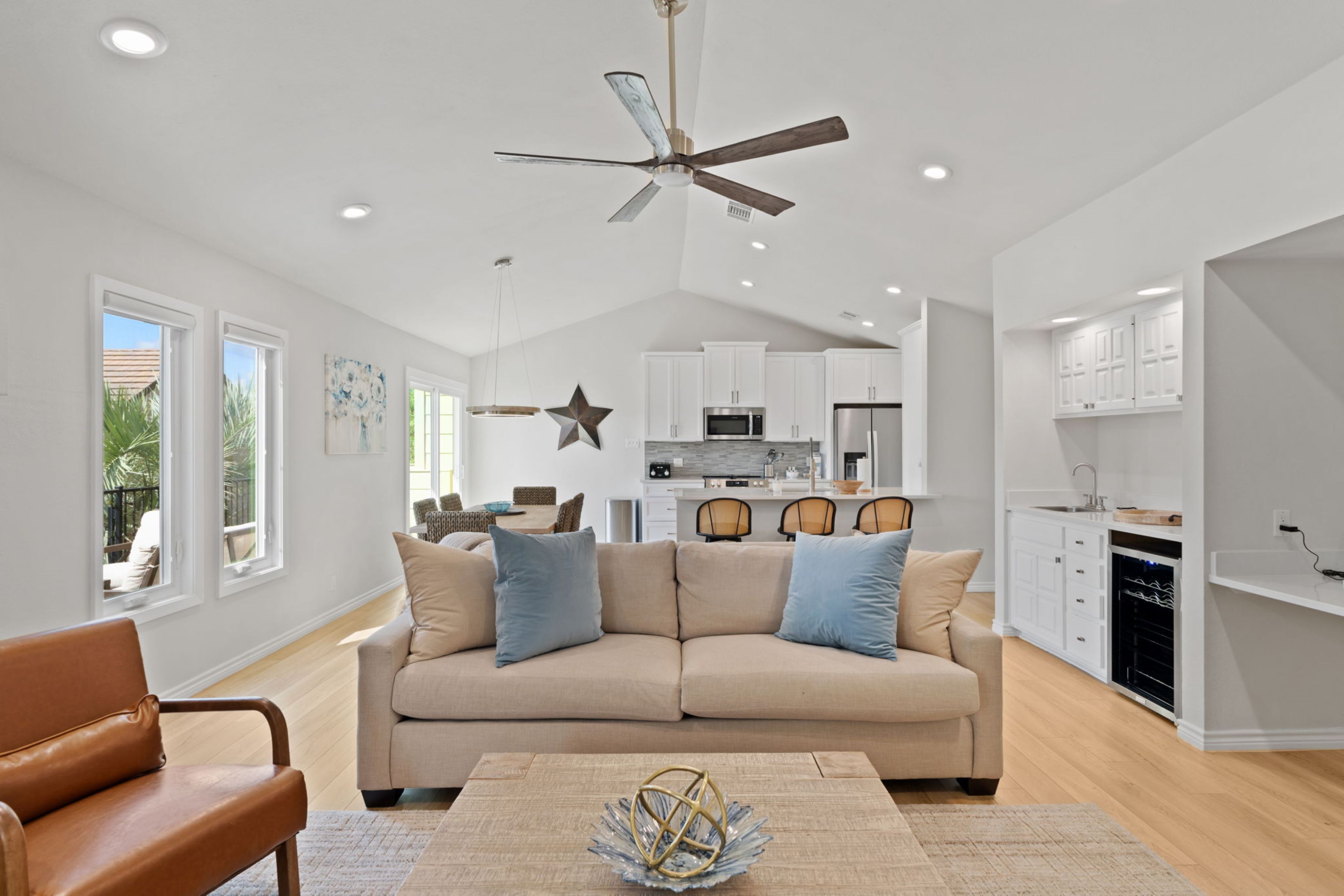 A modern living room with a beige sofa, a coffee table, and a ceiling fan.