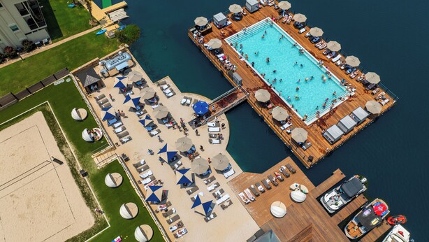 An aerial view of a resort with a central swimming pool, sun loungers, and a dock with boats. - Horseshoe Bay Resort (Horseshoe Bay)
