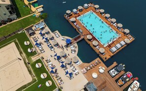 An aerial view of a resort with a central swimming pool, sun loungers, and a dock with boats. - Horseshoe Bay Resort (Horseshoe Bay)