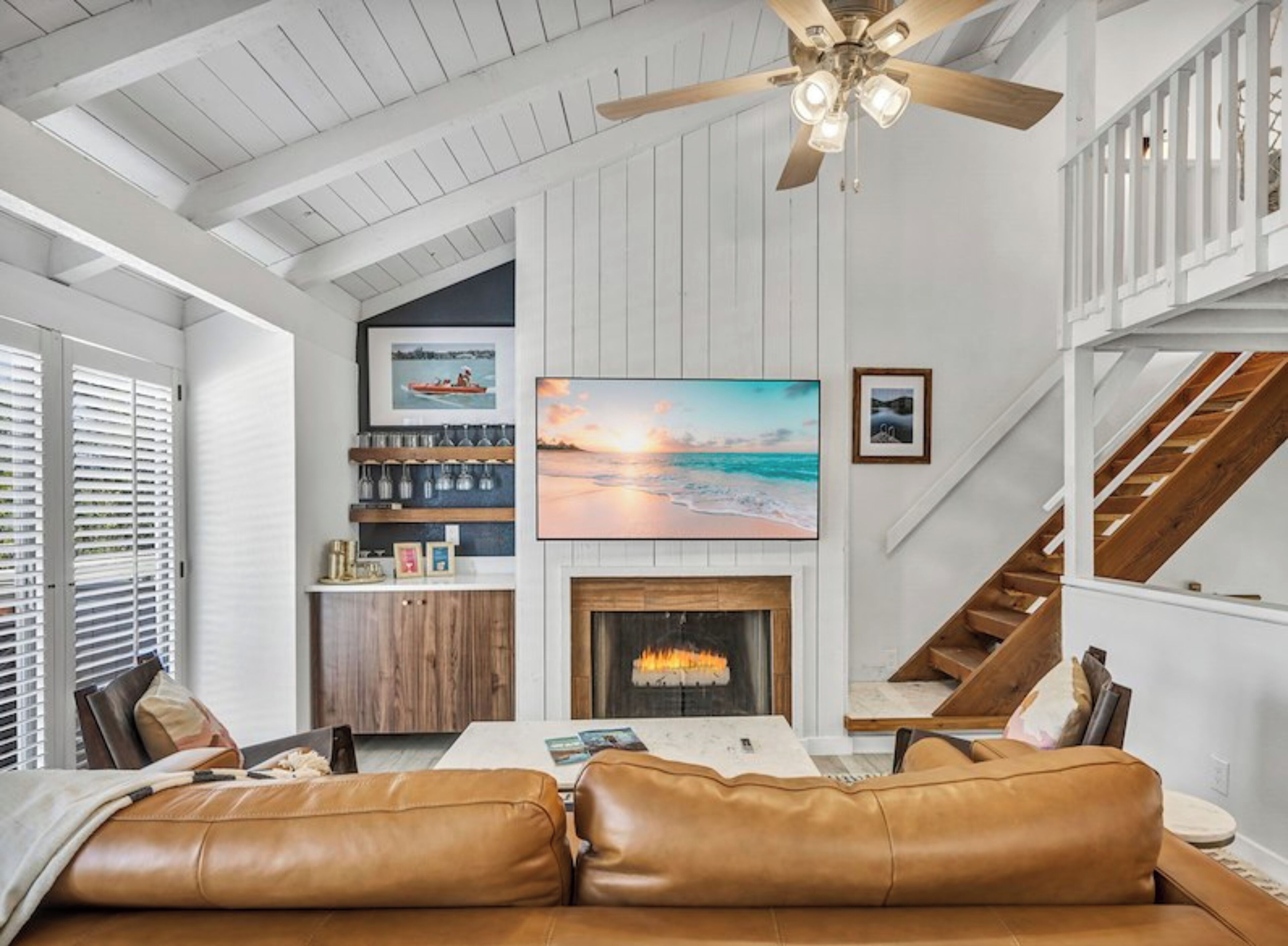 A living room with a fireplace, a large painting, and a staircase.