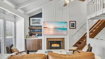 A living room with a fireplace, a large painting, and a staircase.
